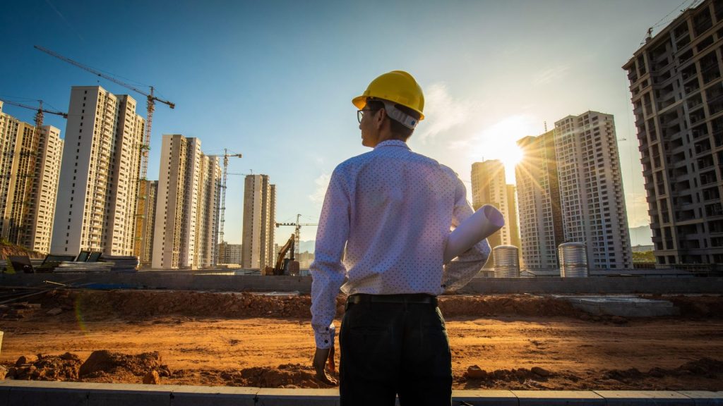 Man looking to the buildings with a sunrise behind the building