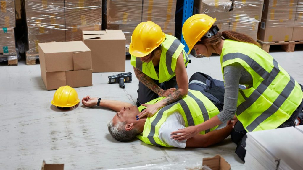 2 people helping a injured construction worker - workplace safety management